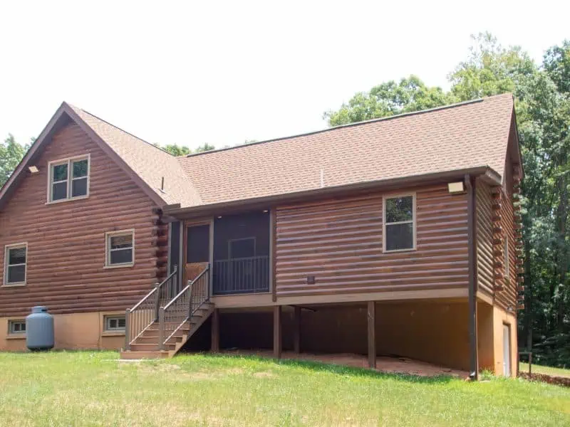 Rear view of an Appomattox home addition with pine log siding stained to match the existing log home and screened porch.
