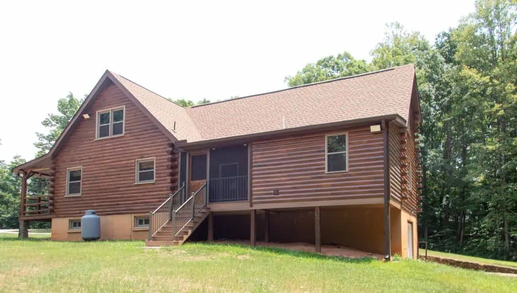 Rear view of an Appomattox home addition with pine log siding stained to match the existing log home and screened porch.