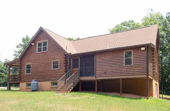 Rear view of an Appomattox home addition with pine log siding stained to match the existing log home and screened porch.